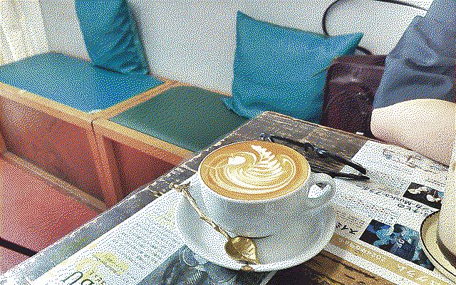 A large cup of coffee with beautiful latte art and a golden spoon in the shape of a leaf