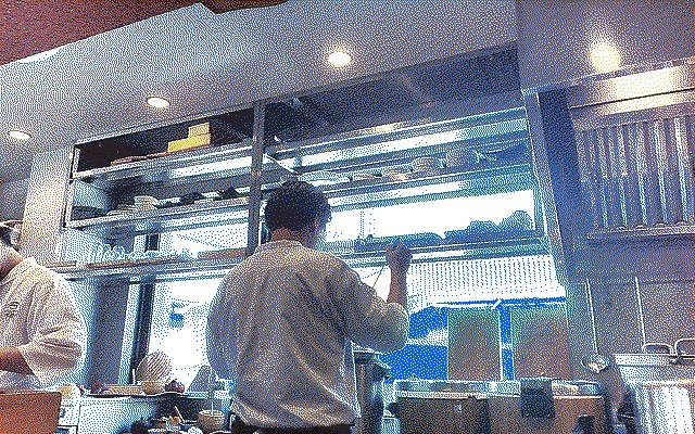 The back of a chef serving some soup