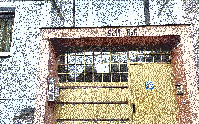 The entrance of an apartment block that’s yellow and orange with a funky gridded window