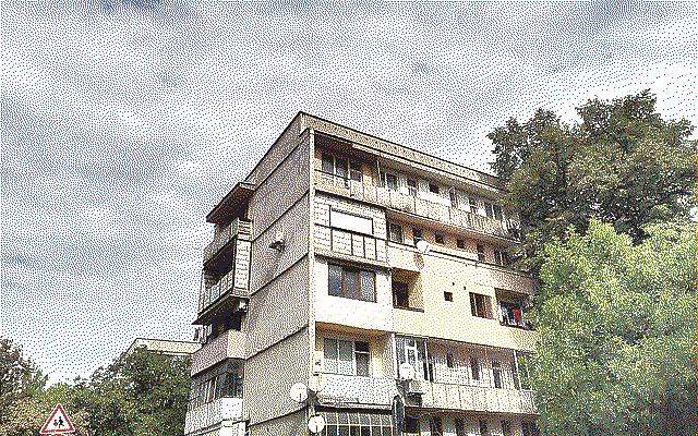 A grey apartment block surrounded by trees