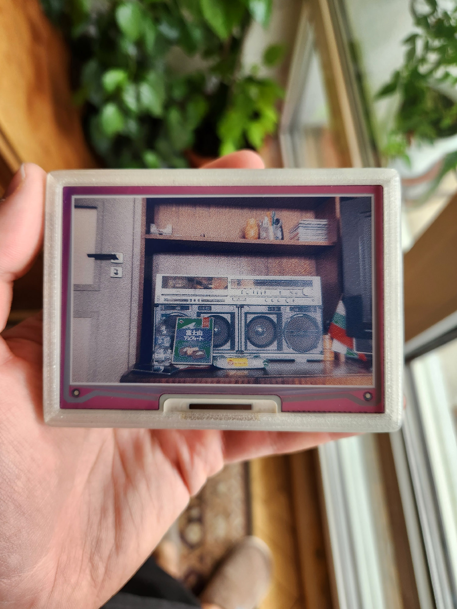 A photo of a hand holding eink.cam with the above photo displayed on it.