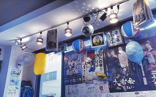 An arrangement of various lights, lanterns and a disco ball. On the wall there’s a variety of posters with figures dressed in traditional outfits.