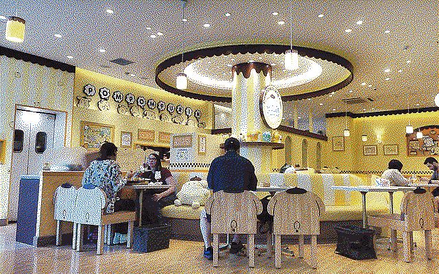 People enjoying the Pompompurin cafe sitting on chairs that are in the shape of the dog