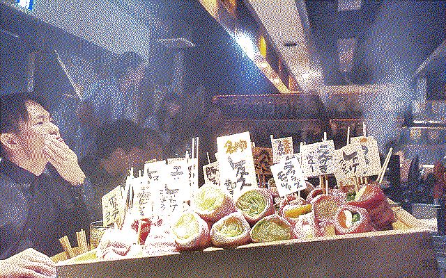 big platter of uncooked vegetable skewers and a guy pondering on the left